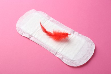 Menstrual pad with red feather on pink background