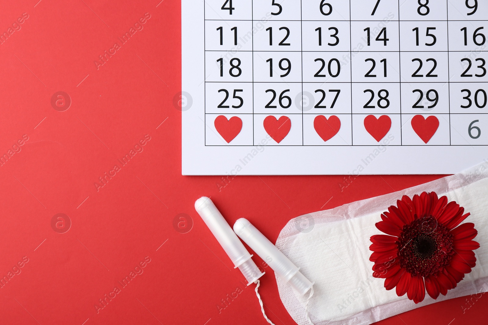 Photo of Flat lay composition with calendar and menstrual products on red background