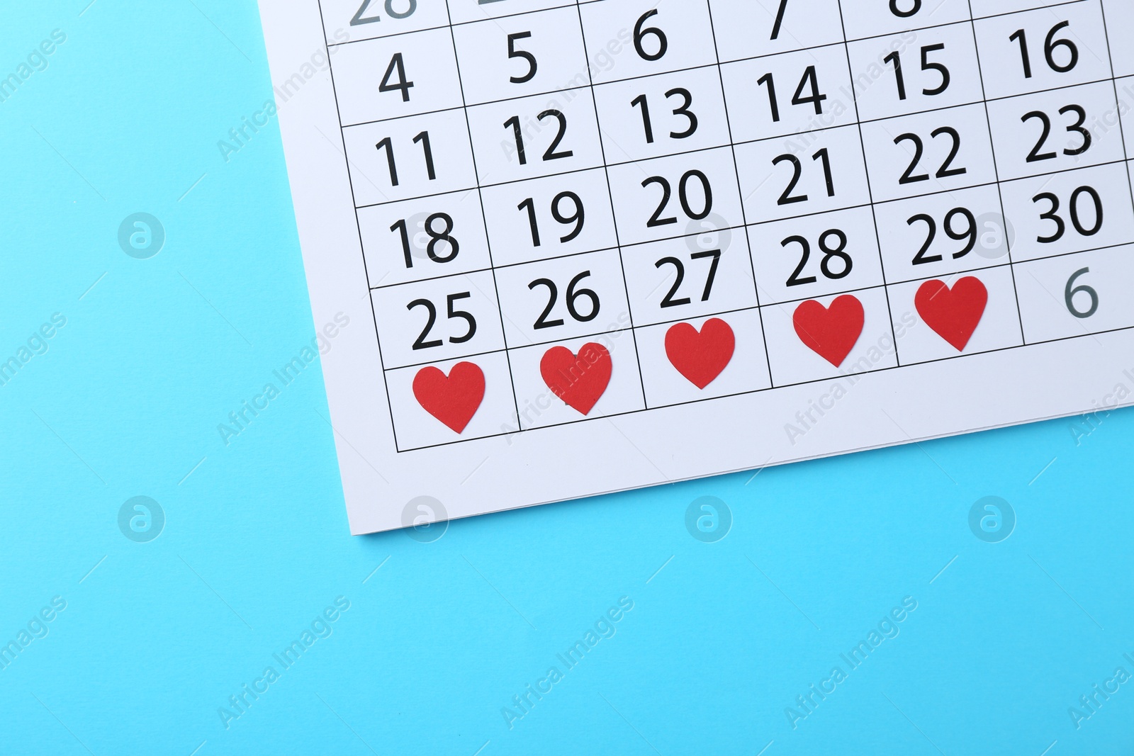 Photo of Menstruation. Calendar with marked dates on light blue background, top view