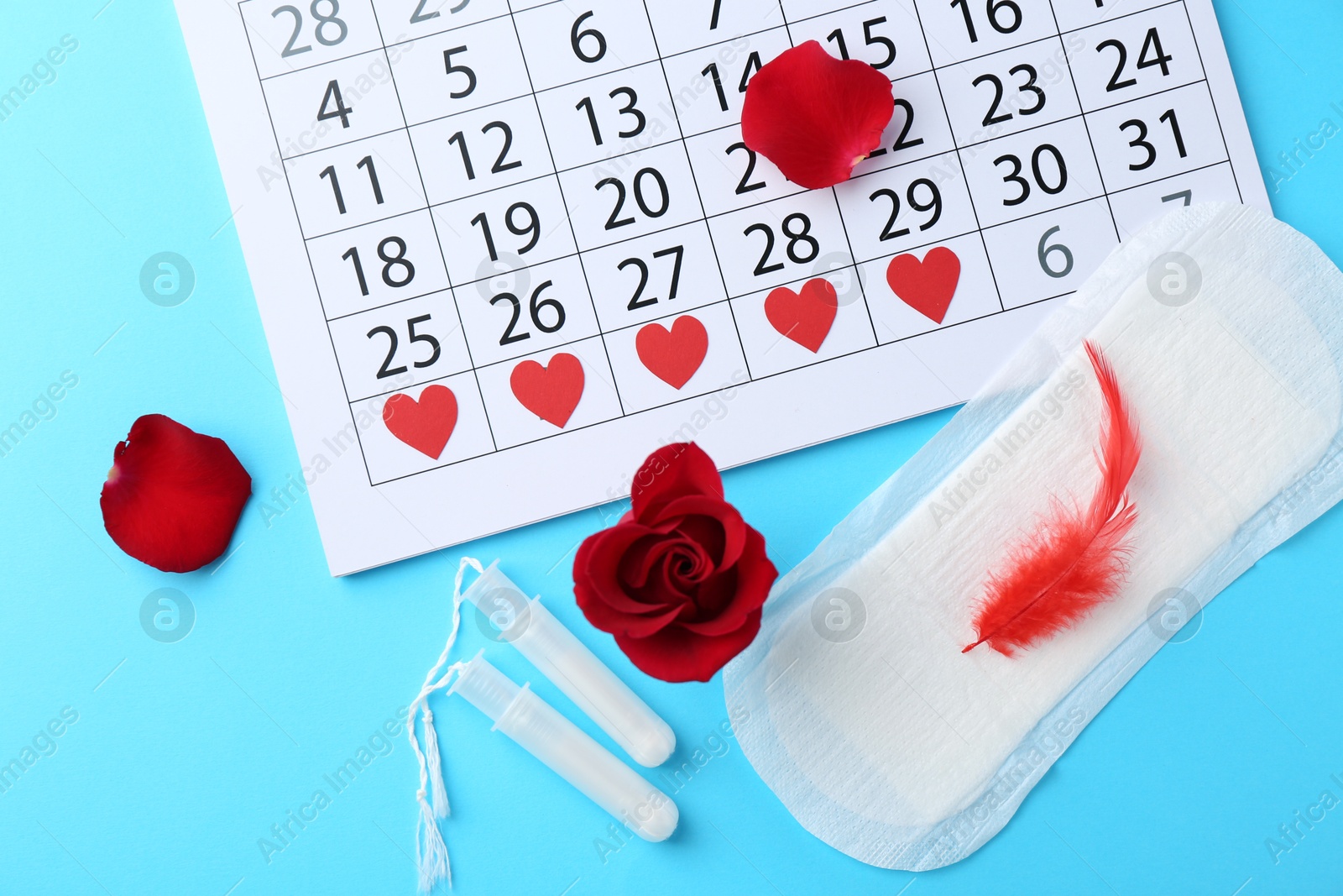 Photo of Flat lay composition with calendar and menstrual products on light blue background