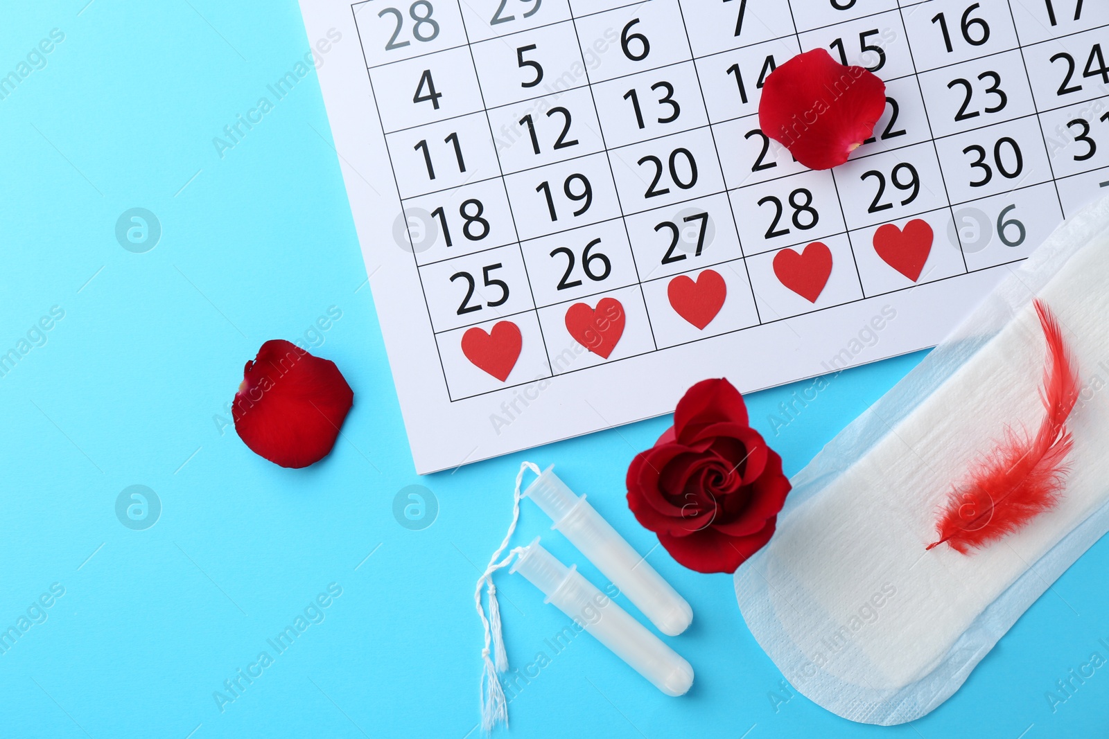 Photo of Flat lay composition with calendar and menstrual products on light blue background