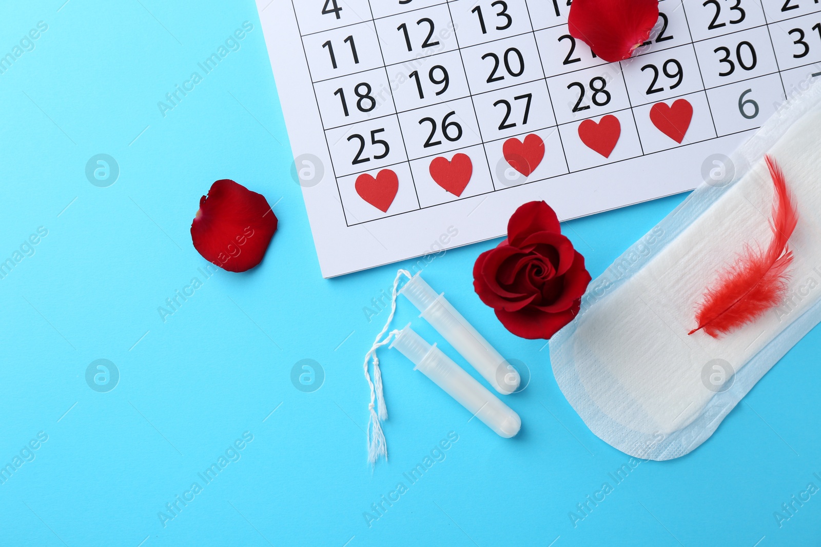 Photo of Flat lay composition with calendar and menstrual products on light blue background