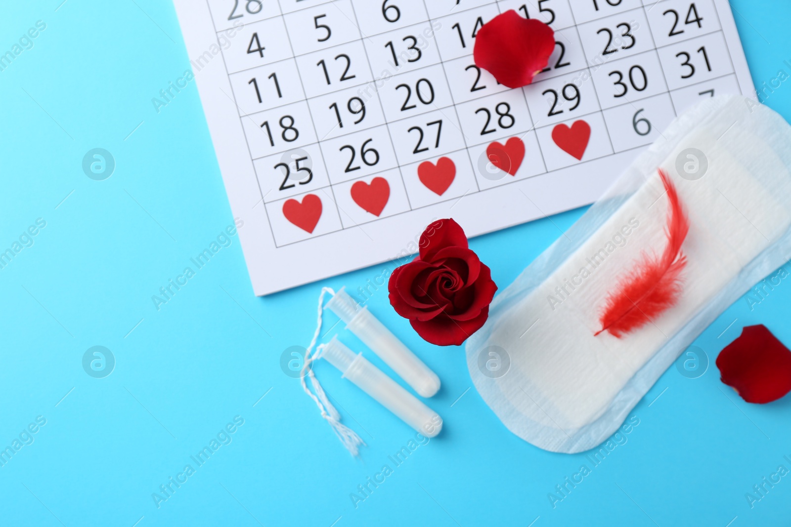 Photo of Flat lay composition with calendar and menstrual products on light blue background