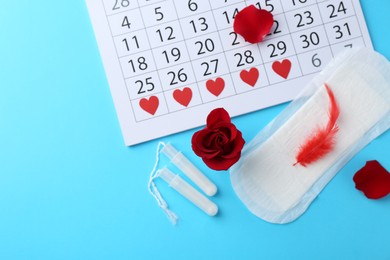 Flat lay composition with calendar and menstrual products on light blue background