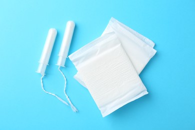 Photo of Menstrual pads and tampons on light blue background, top view