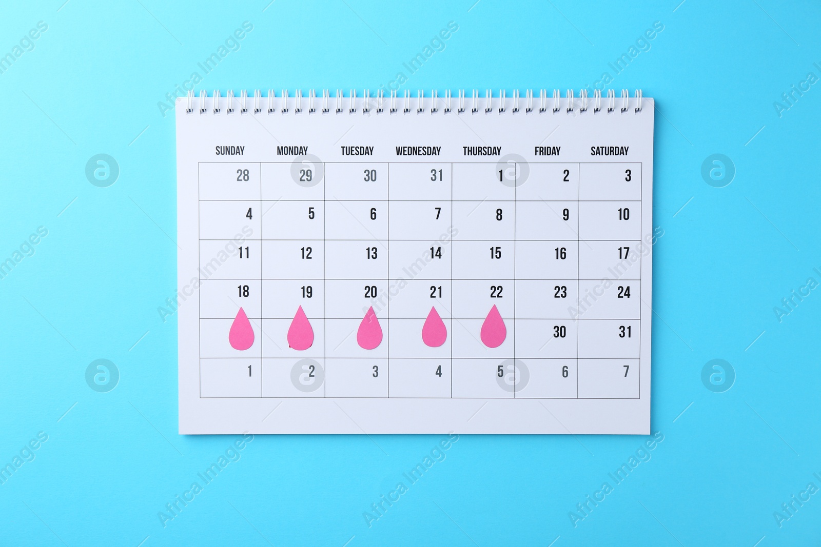 Photo of Menstruation. Calendar with marked dates on light blue background, top view