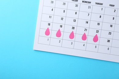 Photo of Menstruation. Calendar with marked dates on light blue background, top view