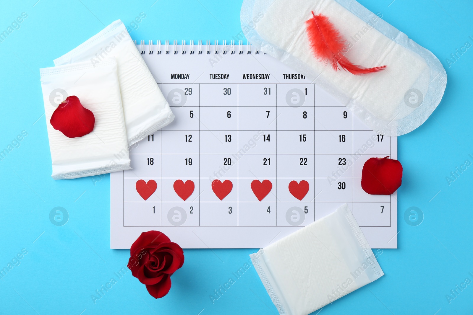 Photo of Flat lay composition with calendar and menstrual products on light blue background