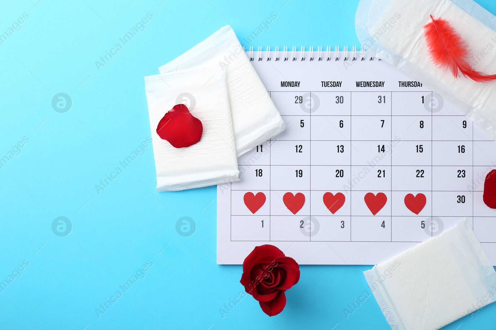 Photo of Flat lay composition with calendar and menstrual products on light blue background