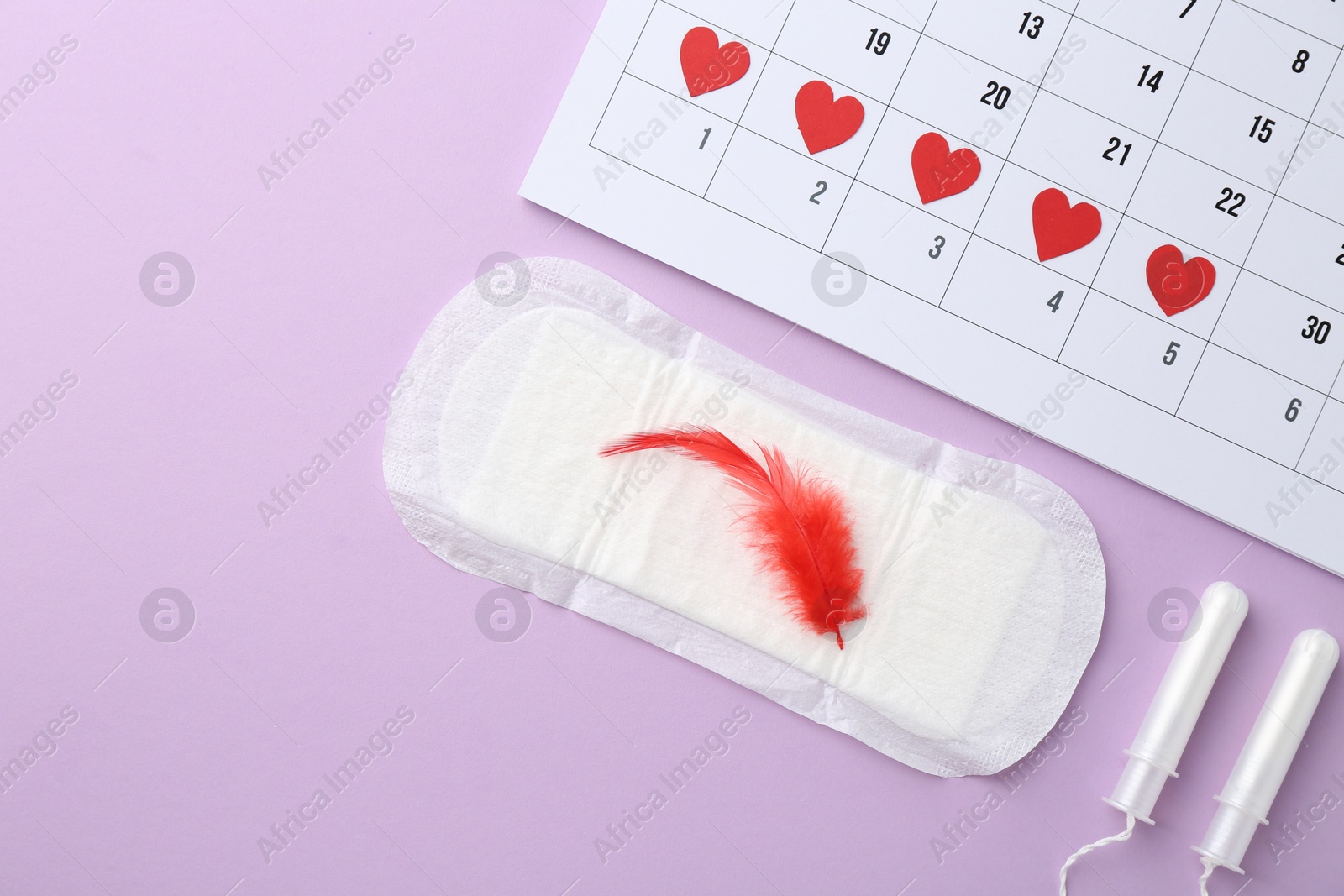 Photo of Flat lay composition with calendar and menstrual products on violet background