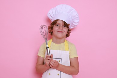 Photo of Little boy with whisk pretending to be chef on pink background. Dreaming about future profession