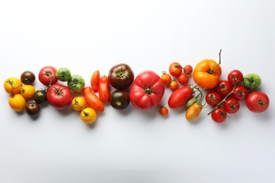 Different ripe tomatoes on white background, flat lay