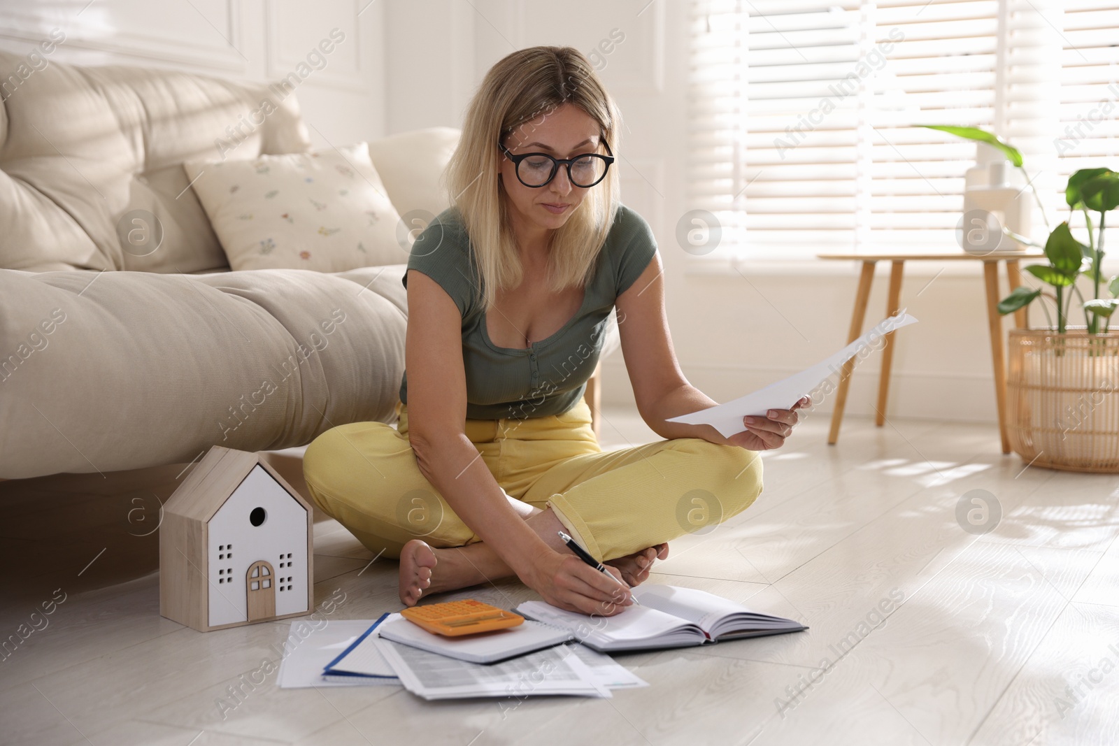 Photo of Budget planning. Woman working with accounting documents on floor indoors