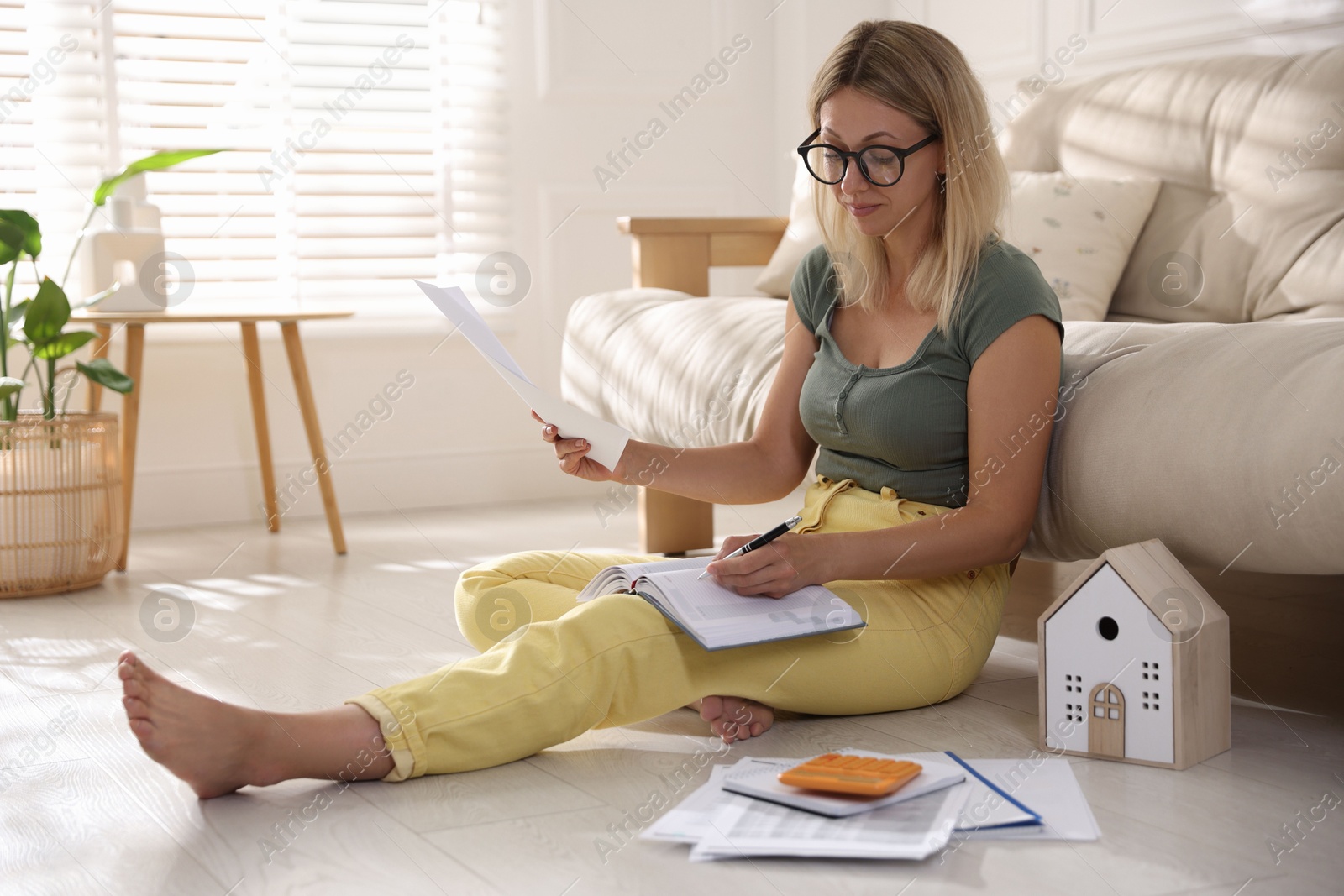 Photo of Budget planning. Woman working with accounting documents on floor indoors