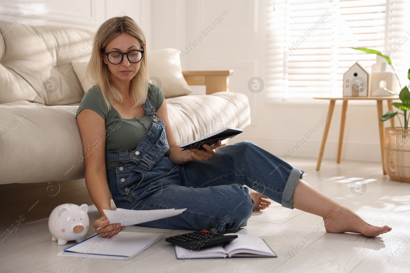 Photo of Budget planning. Woman working with accounting documents on floor indoors