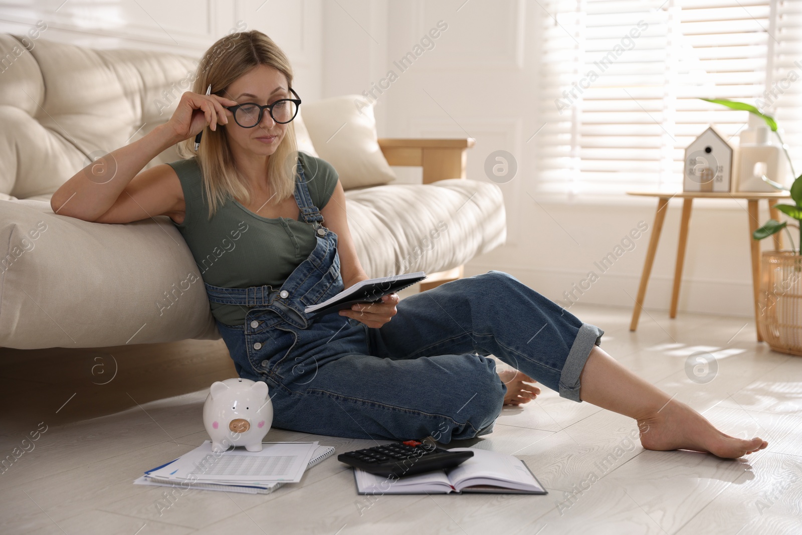 Photo of Budget planning. Woman working with accounting documents on floor indoors