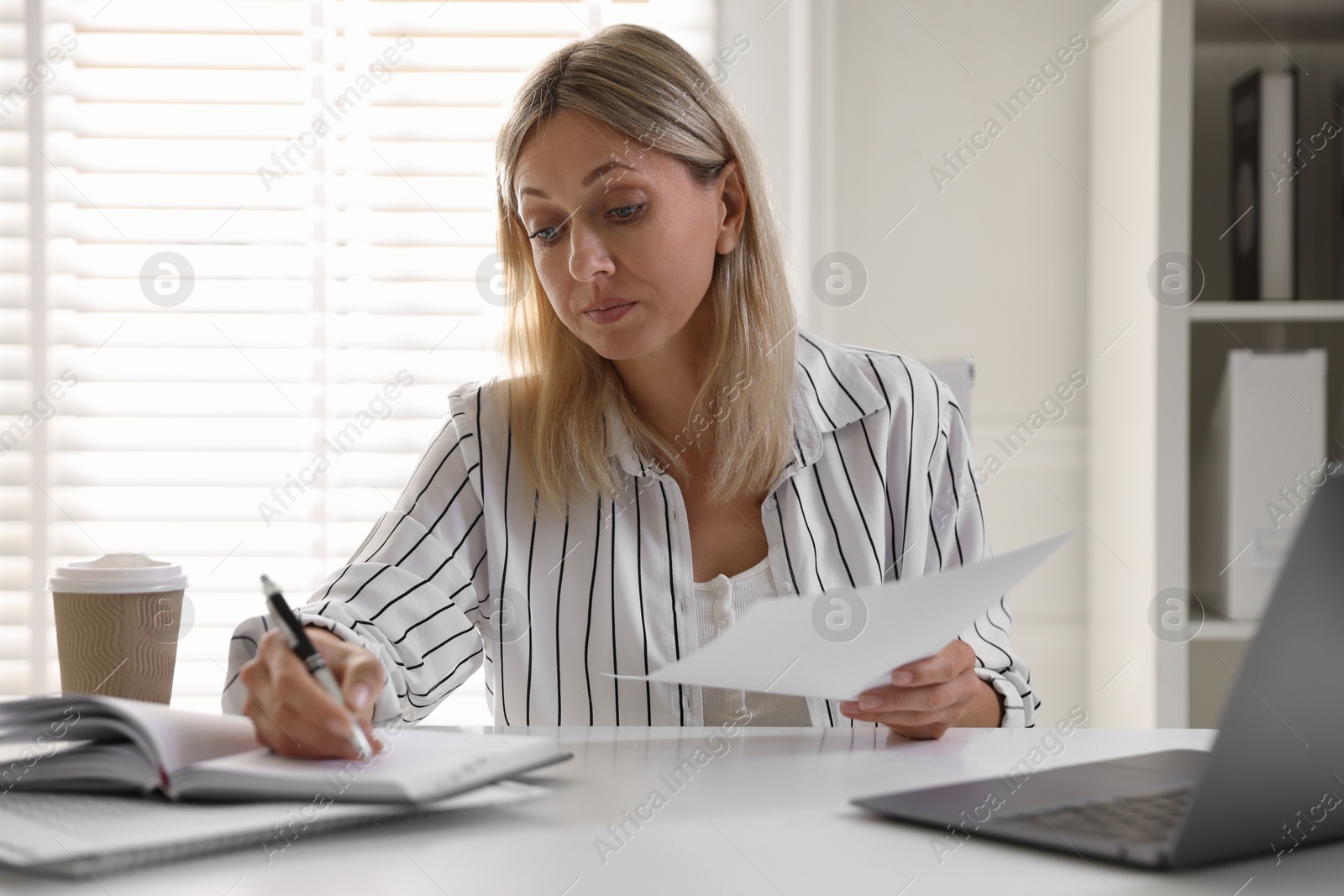 Photo of Budget planning. Woman with document taking notes at table indoors