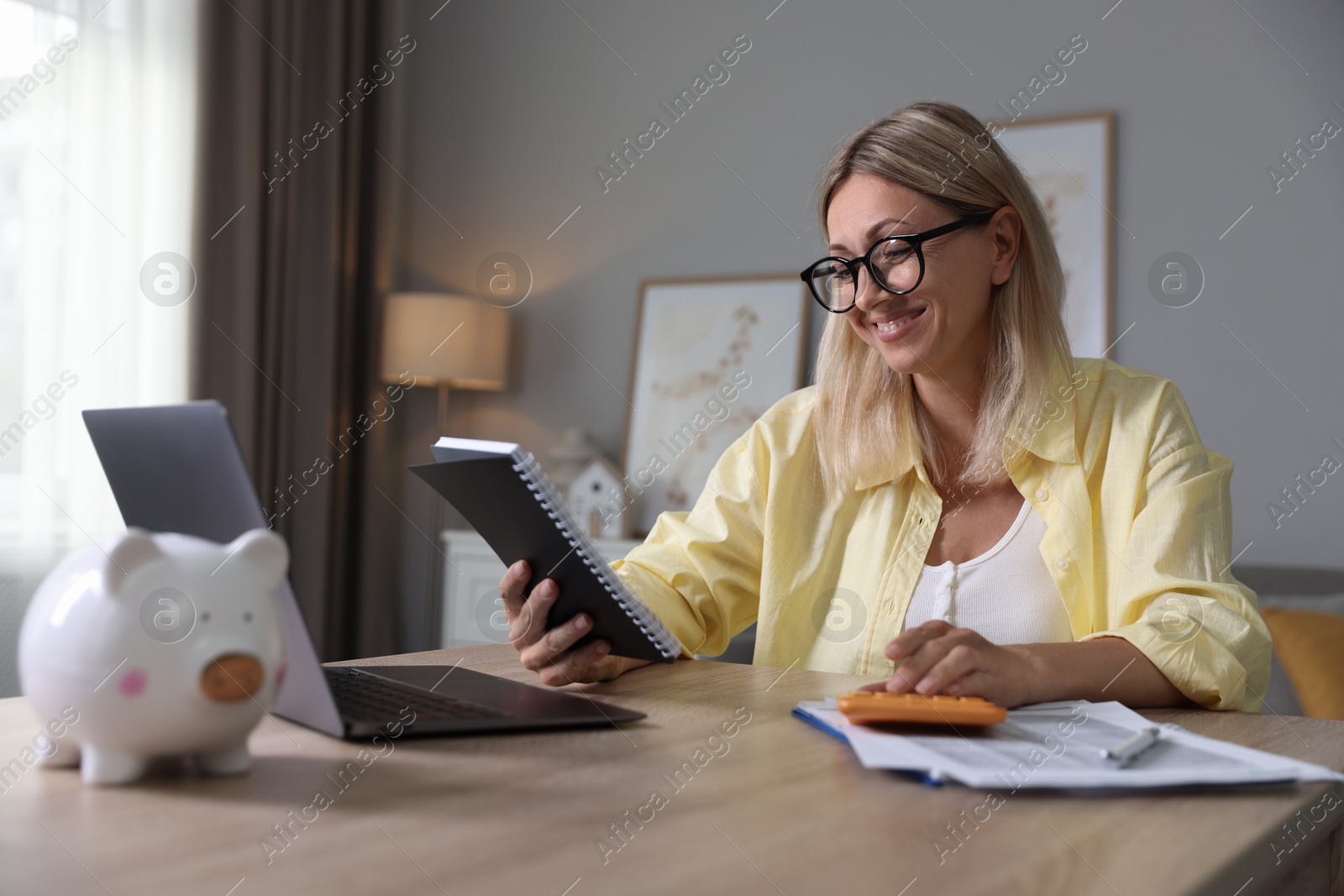 Photo of Budget planning. Woman with notebook using calculator at table indoors