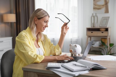 Photo of Budget planning. Woman using laptop at table indoors