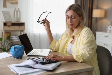 Budget planning. Woman using calculator at table indoors