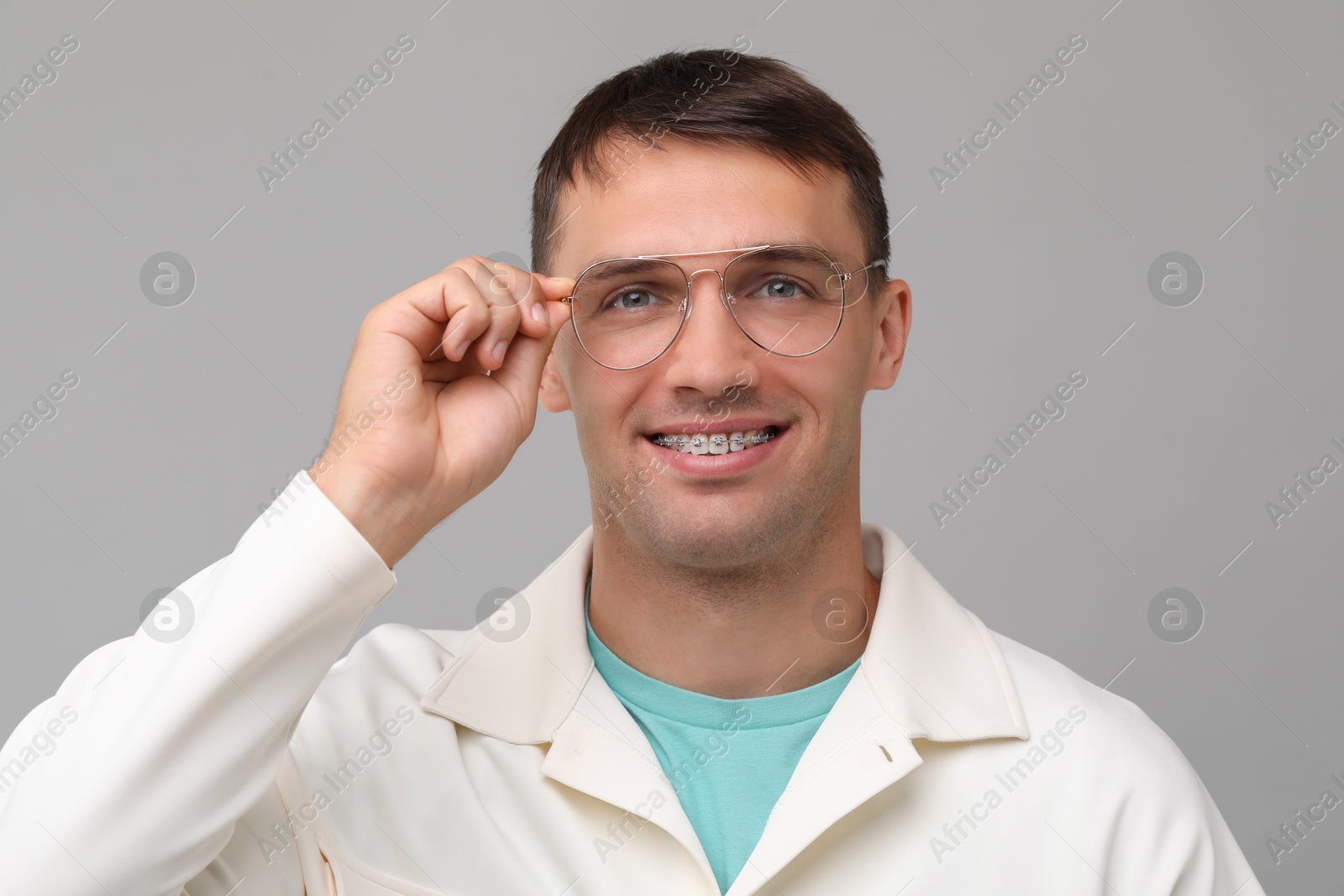 Photo of Smiling man with dental braces on grey background