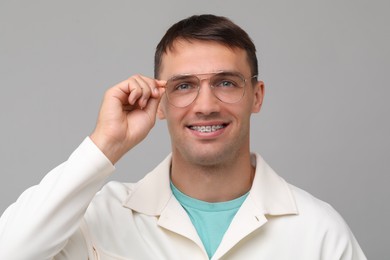 Smiling man with dental braces on grey background