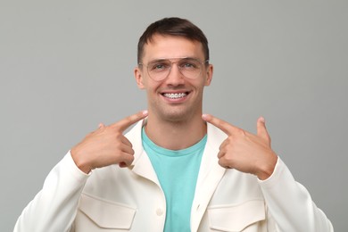 Photo of Happy man pointing at his dental braces on grey background