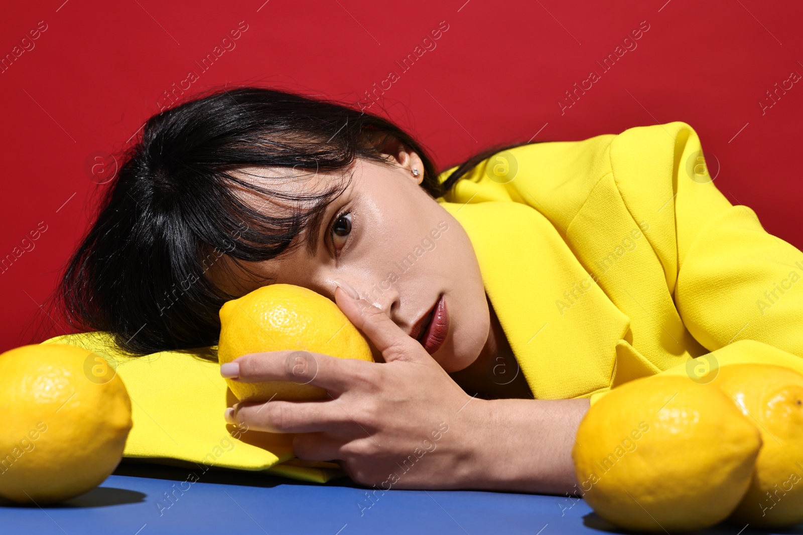 Photo of Woman with lemons at blue table on red background