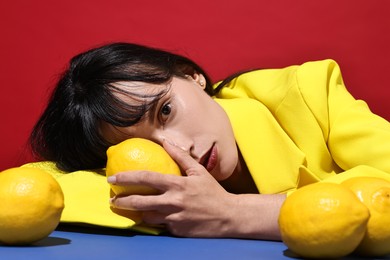 Woman with lemons at blue table on red background