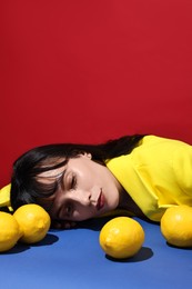 Woman with lemons at blue table on red background