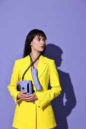 Woman in yellow jacket with corded telephone on purple background