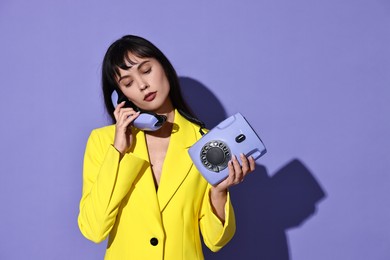 Photo of Woman in yellow jacket with corded telephone on purple background