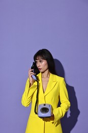 Photo of Woman in yellow jacket with corded telephone on purple background