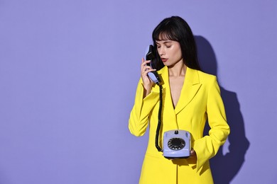 Photo of Woman in yellow jacket with corded telephone on purple background, space for text