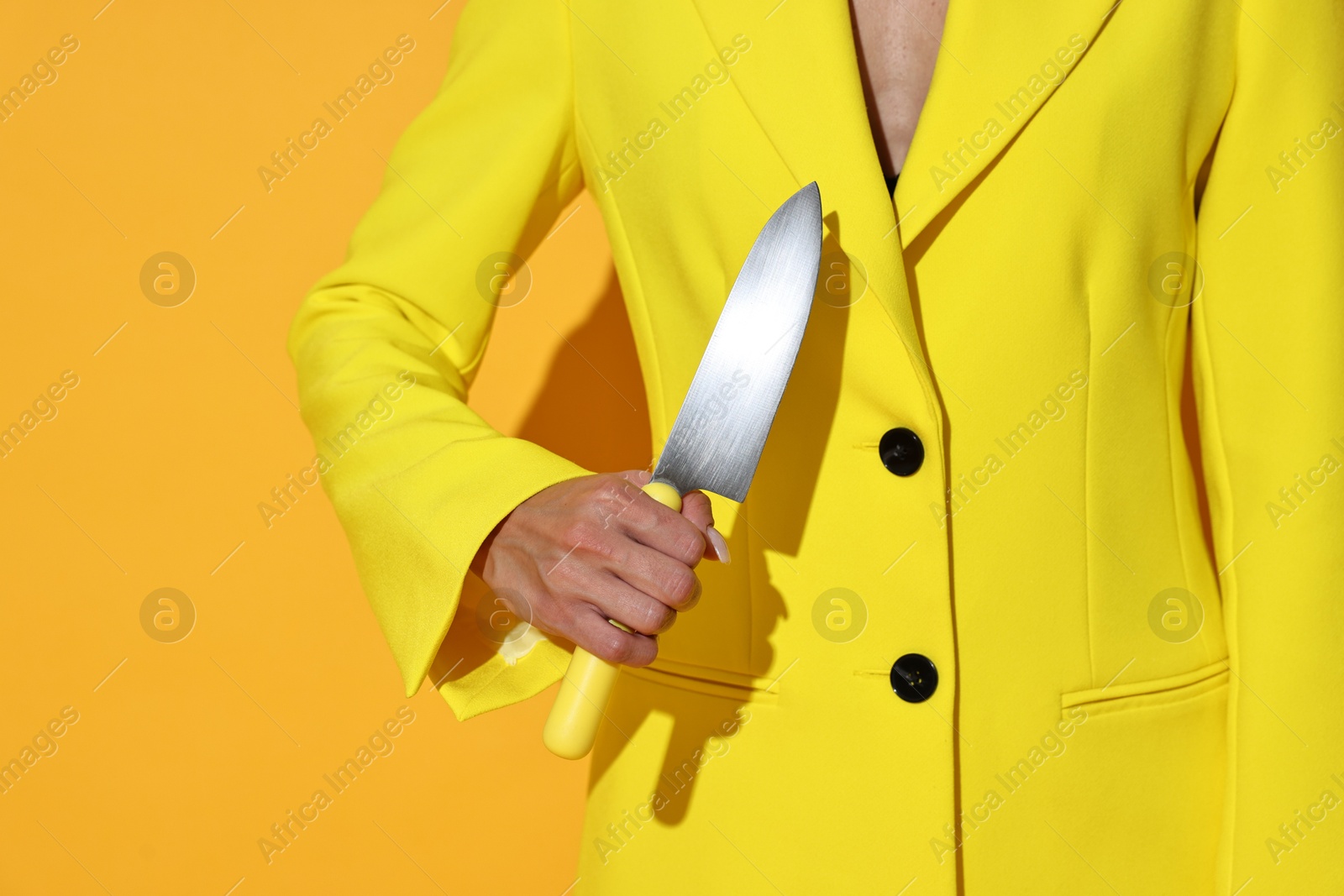 Photo of Woman with sharp knife on yellow background, closeup