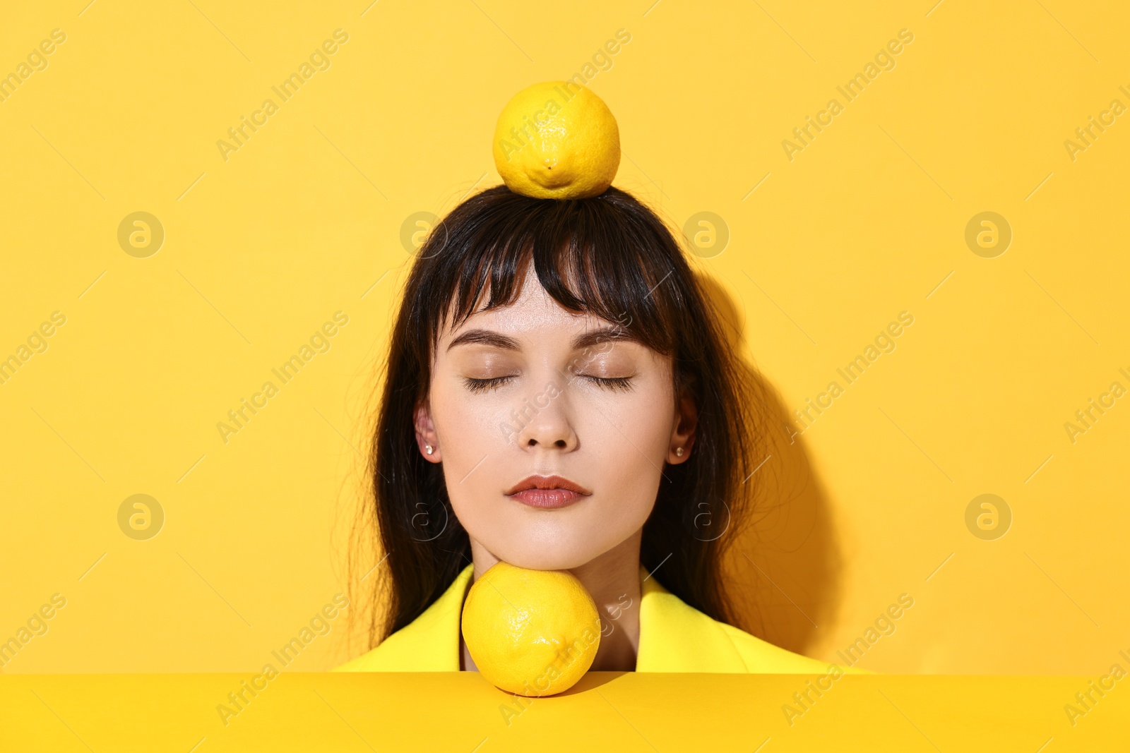 Photo of Young woman with lemons on yellow background