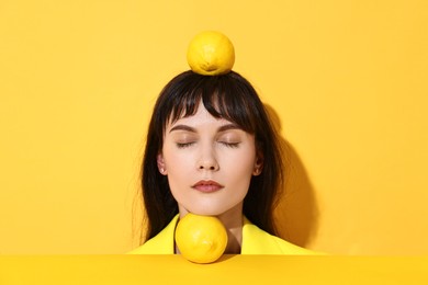 Young woman with lemons on yellow background