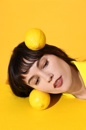 Photo of Young woman with lemons on yellow background