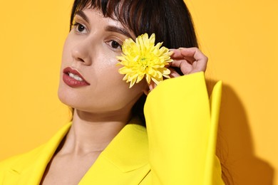 Photo of Woman with beautiful flower on yellow background