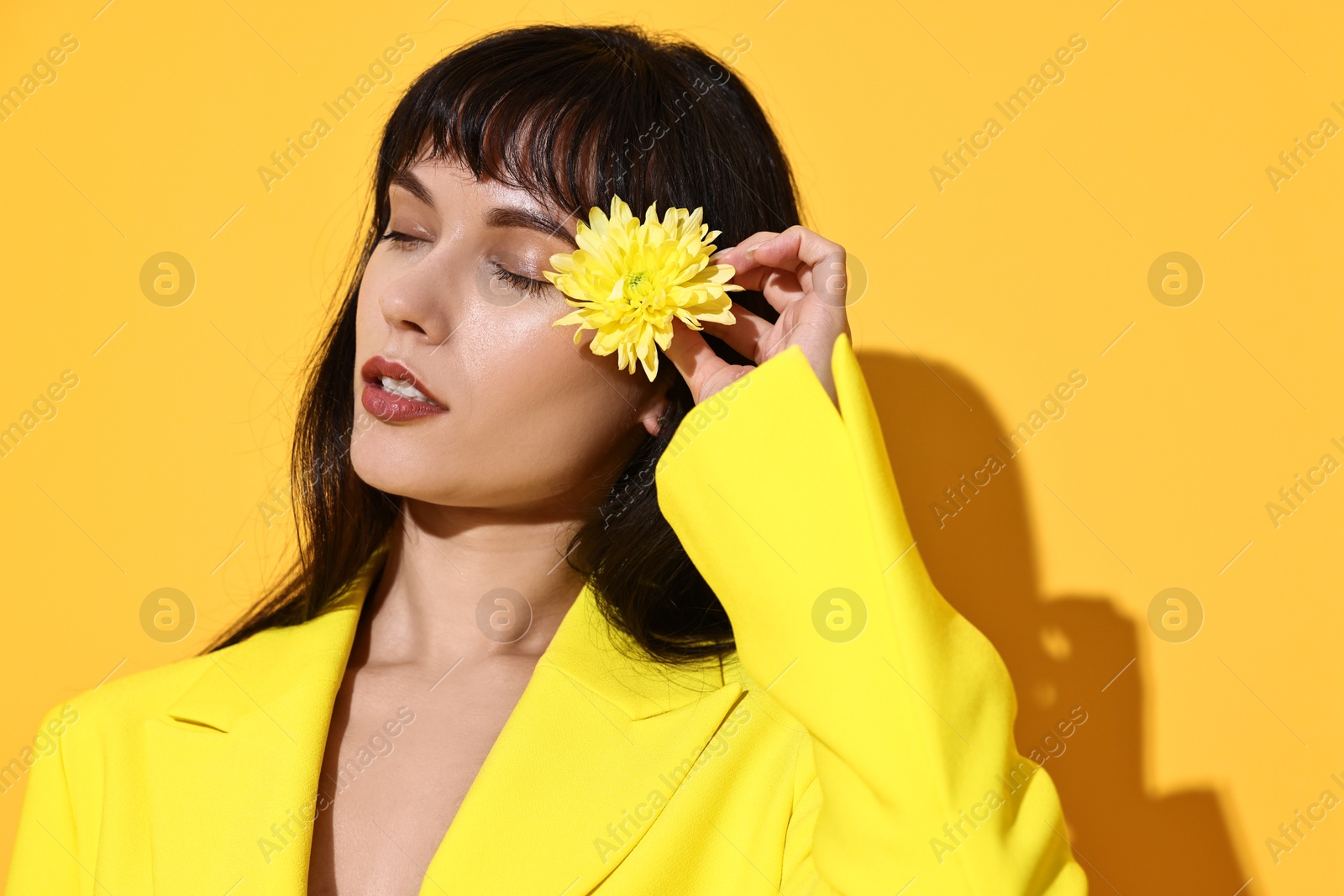 Photo of Woman with beautiful flower on yellow background