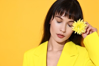 Photo of Woman with beautiful flower on yellow background, space for text