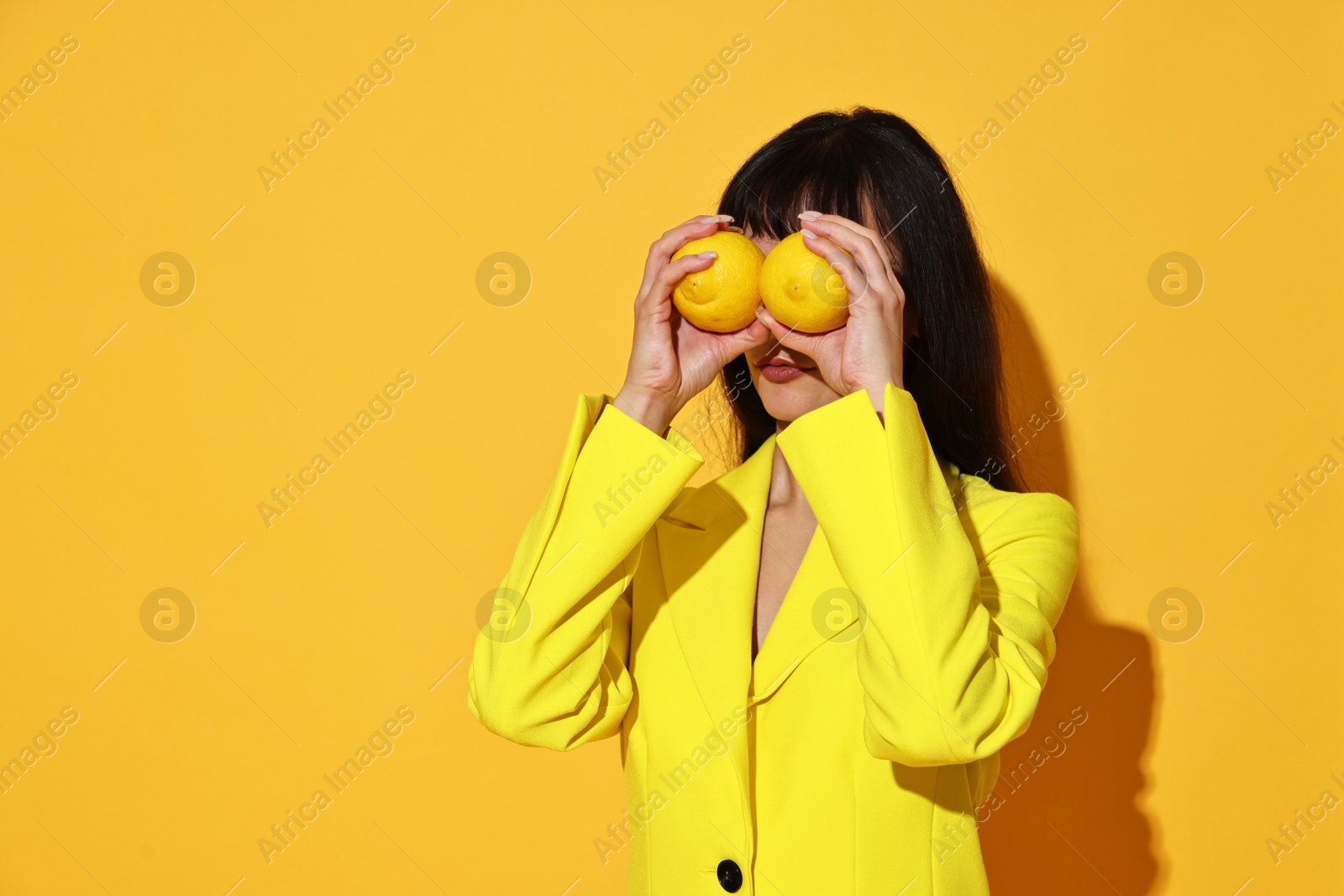 Photo of Young woman with lemons on yellow background, space for text