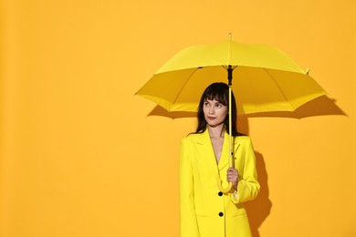 Photo of Woman with open umbrella on yellow background, space for text