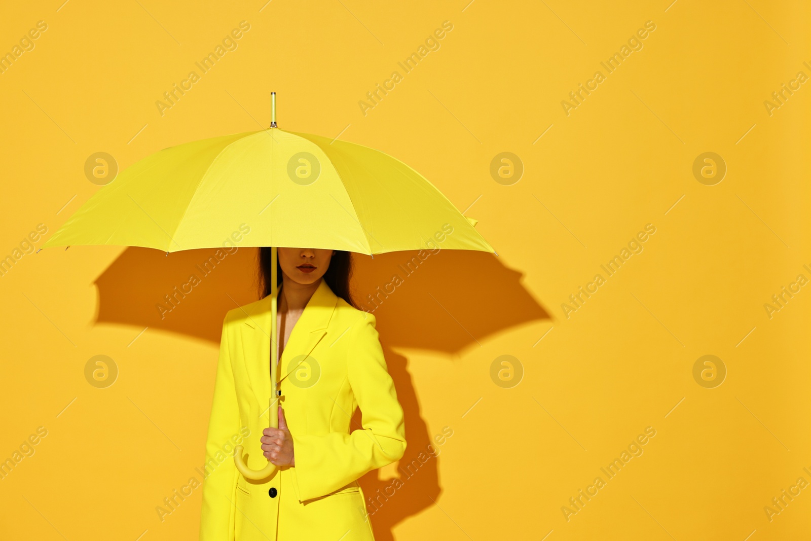 Photo of Woman with open umbrella on yellow background, space for text