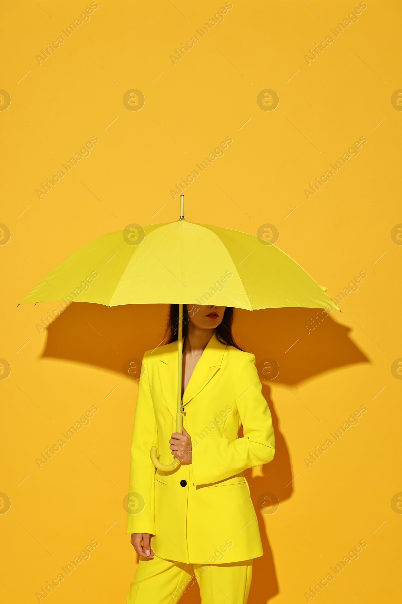 Photo of Woman with open umbrella on yellow background