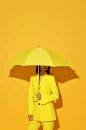 Woman with open umbrella on yellow background