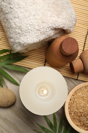 Spa composition with burning candle on wooden table, flat lay