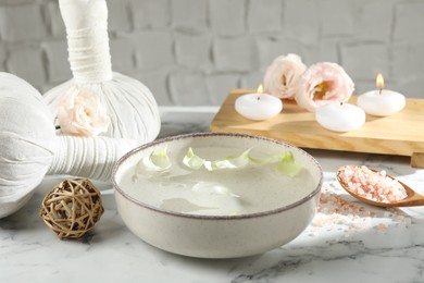 Photo of Spa composition with bowl of water and burning candles on white marble table, closeup