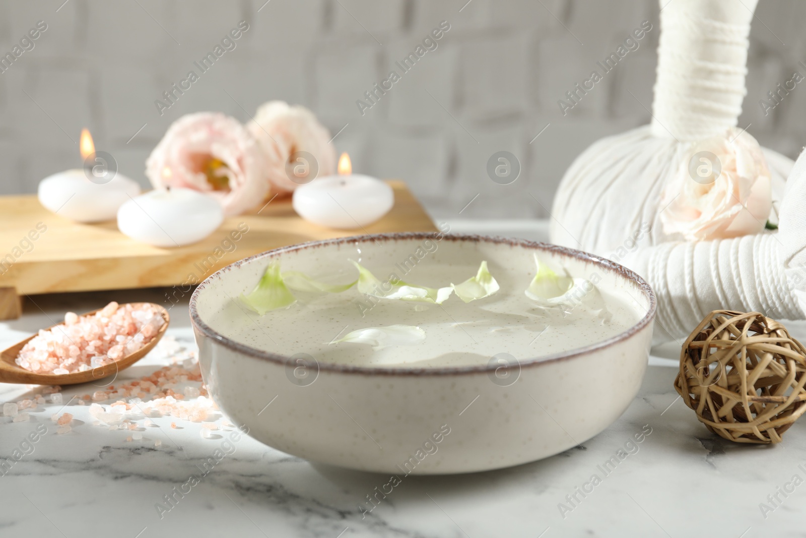 Photo of Spa composition with bowl of water and burning candles on white marble table, closeup