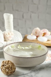 Photo of Spa composition with bowl of water and burning candles on white marble table, closeup